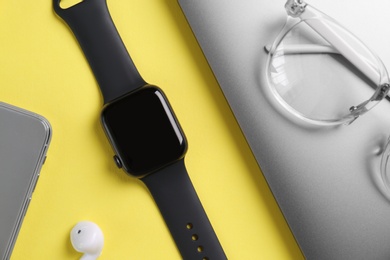 Photo of Flat lay composition with stylish smart watch on yellow background