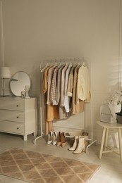 Modern dressing room interior with stylish clothes, shoes and white backpack