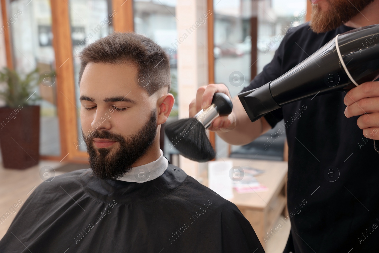 Photo of Professional hairdresser working with client in barbershop, closeup