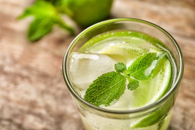 Refreshing beverage with mint and lime in glass on table, closeup