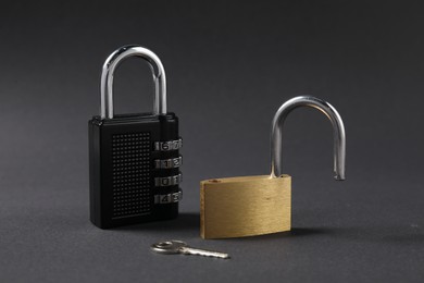 Photo of Different padlocks and key on black background, closeup