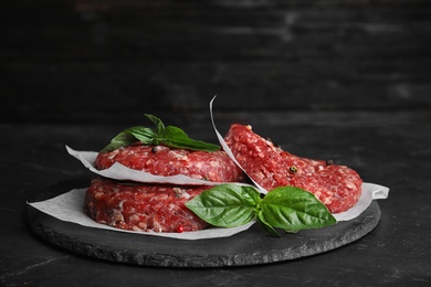 Photo of Raw meat cutlets for burger on black table. Space for text
