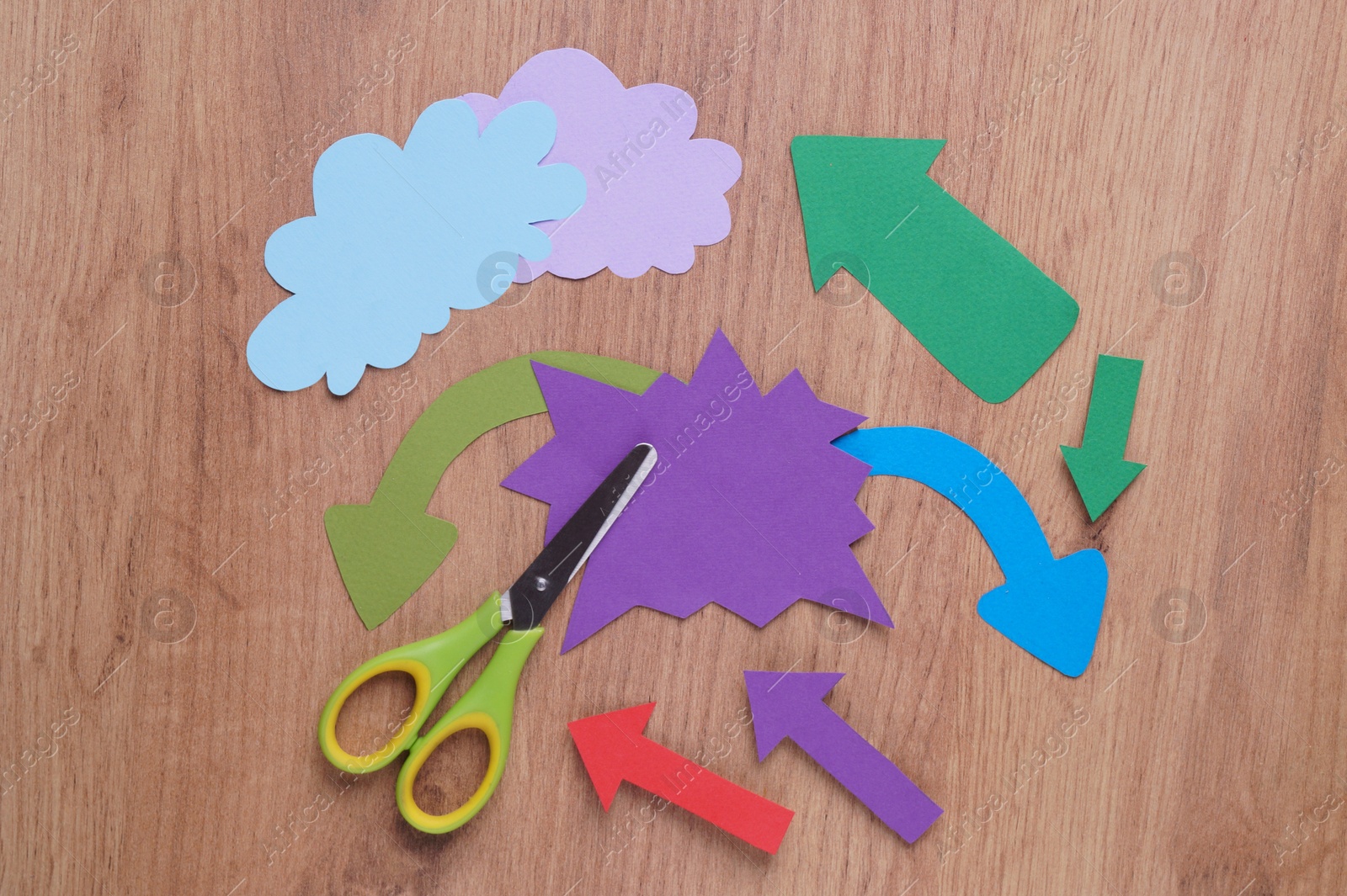 Photo of Scissors and different paper figures on wooden table, flat lay. Space for text