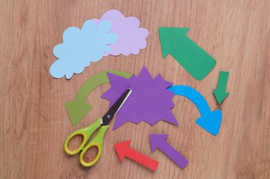 Photo of Scissors and different paper figures on wooden table, flat lay. Space for text