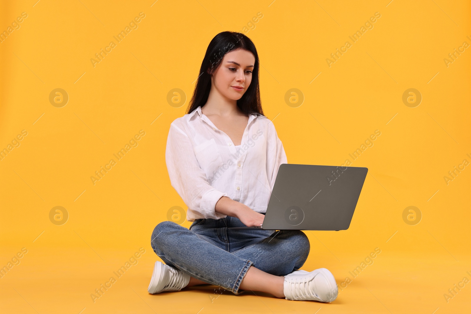 Photo of Student with laptop sitting on yellow background