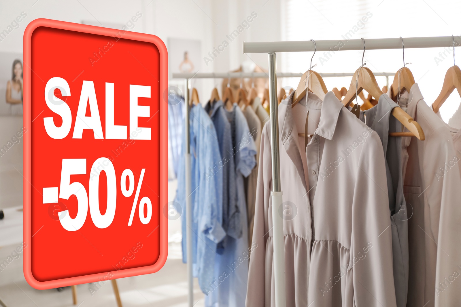 Image of Sale sign and rack with collection of stylish women's clothes in modern boutique