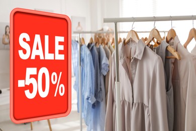 Image of Sale sign and rack with collection of stylish women's clothes in modern boutique