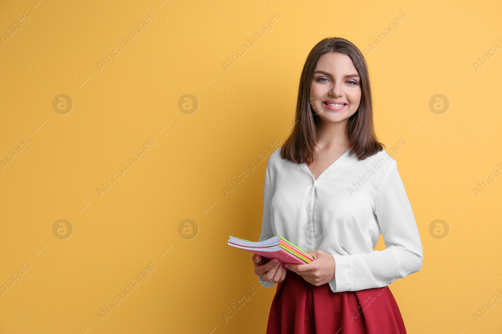 Photo of Portrait of female teacher with notebooks on color background