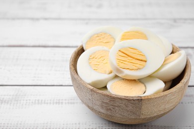 Bowl of fresh hard boiled eggs on white wooden table. Space for text