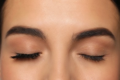 Beautiful young woman showing extended and ordinary eyelashes, closeup