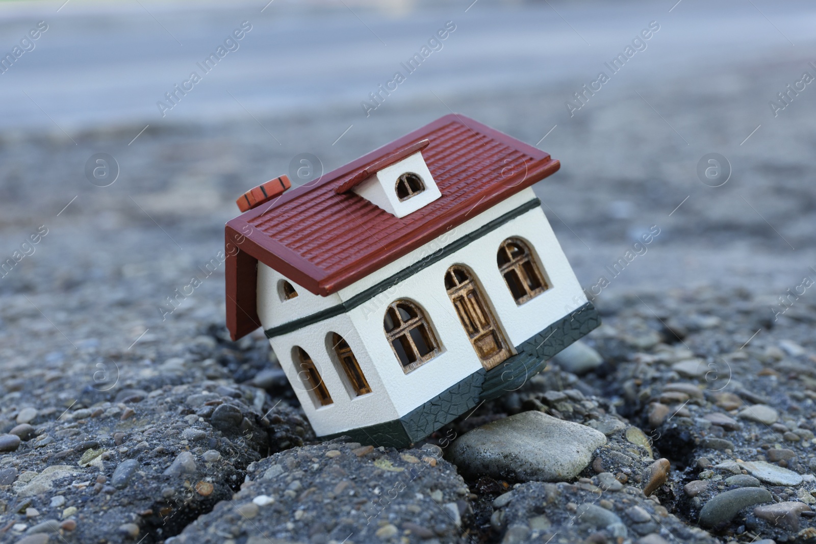 Photo of House model in cracked asphalt. Earthquake disaster