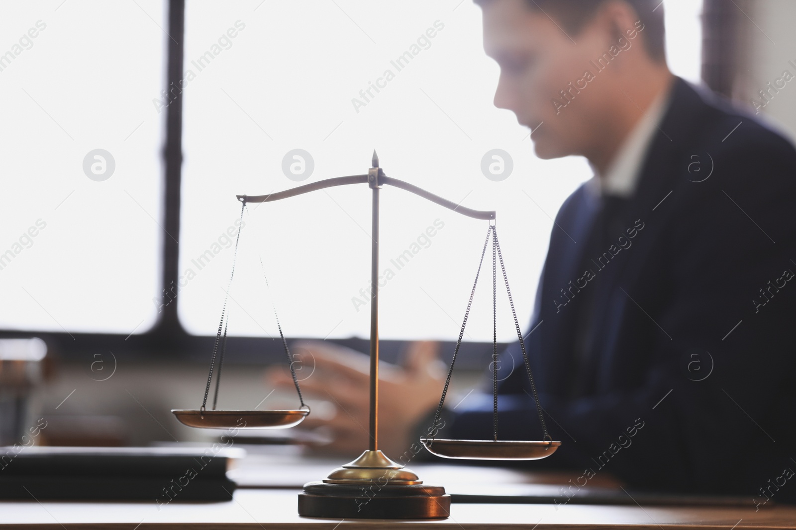 Photo of Scales of justice and blurred lawyer on background