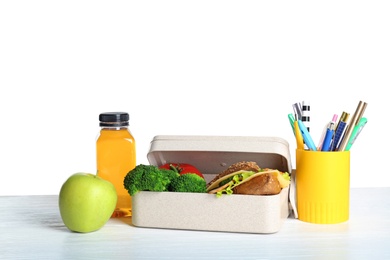 Healthy food and stationery on table against white background. School lunch