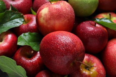 Photo of Pile of wet apples with leaves as background, closeup