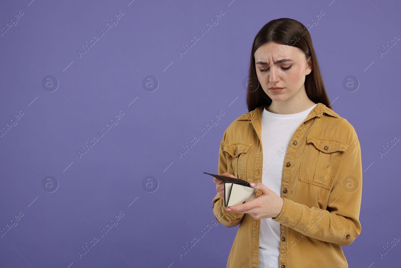 Photo of Sad woman with empty wallet on purple background, space for text