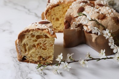Photo of Delicious Italian Easter dove cake (traditional Colomba di Pasqua) and flowers on white table, closeup