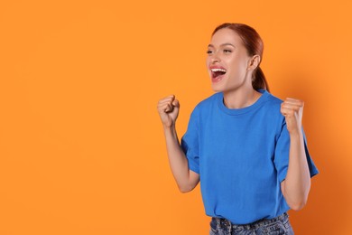 Photo of Excited sports fan celebrating on orange background, space for text