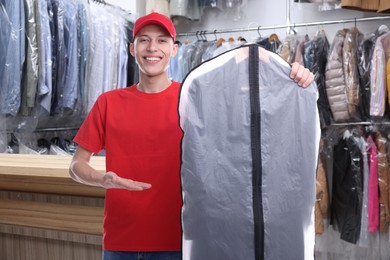 Image of Happy courier holding garment cover with clothes in dry-cleaning
