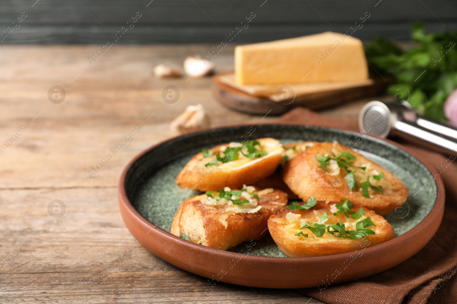 Photo of Slices of toasted bread with garlic, cheese and herbs on wooden table