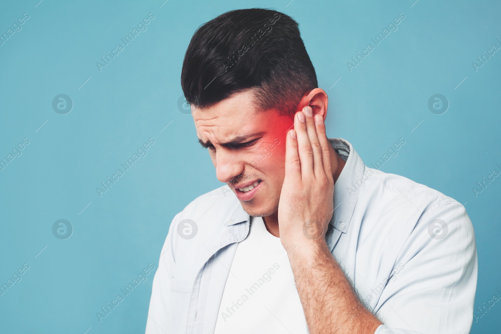 Image of Man suffering from ear pain on light blue background