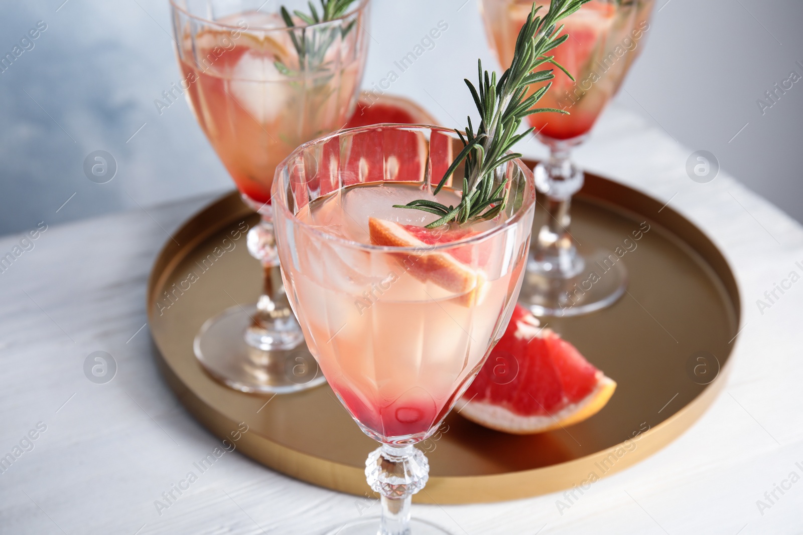 Photo of Glass of grapefruit cocktail on table, closeup