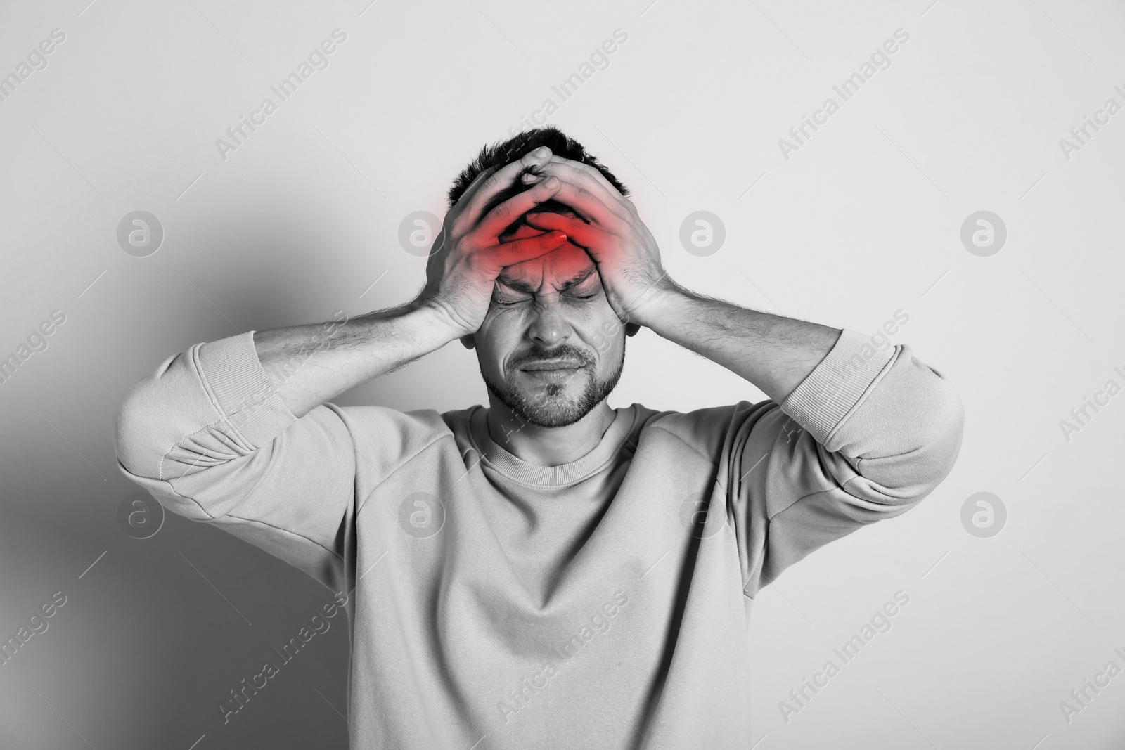 Image of Man suffering from terrible migraine on light background