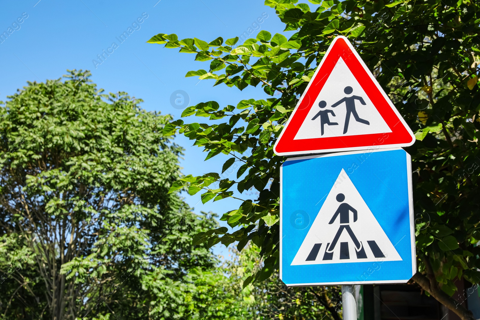 Photo of Different road signs with pedestrians outdoors on sunny day