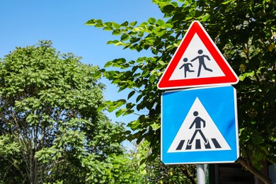 Photo of Different road signs with pedestrians outdoors on sunny day