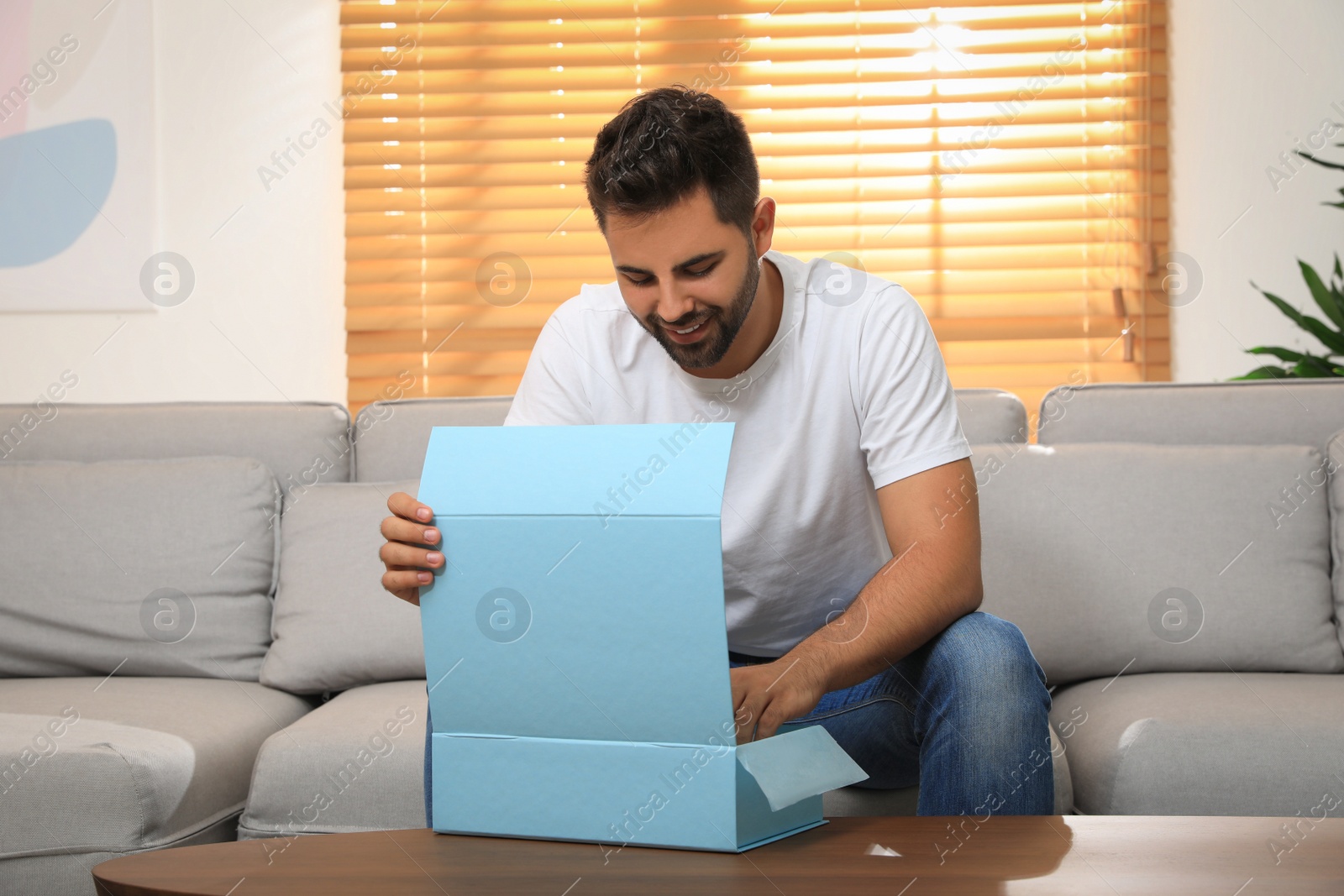 Photo of Man unpacking parcel at home. Online shopping