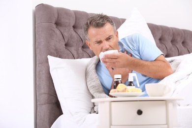 Man suffering from cough and cold in bed at home