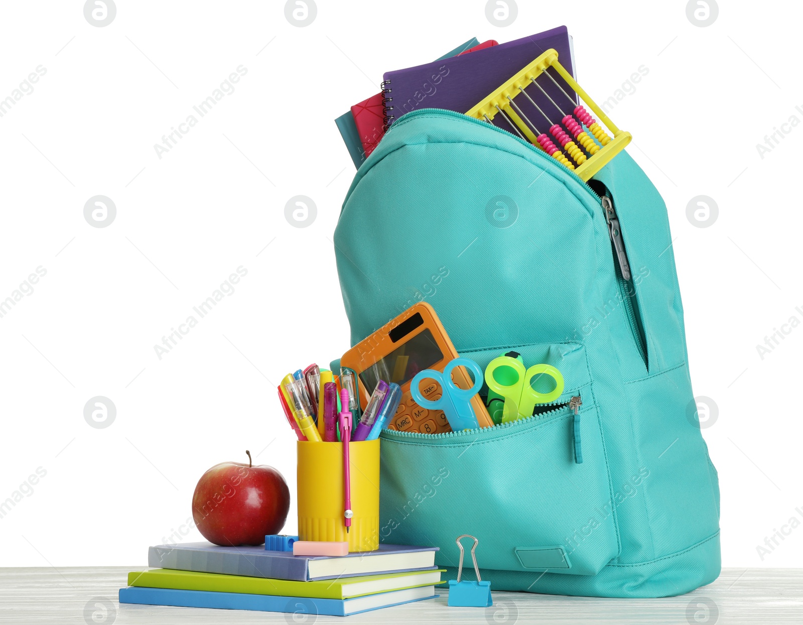 Photo of Stylish backpack with different school stationary and apple on wooden table against white background