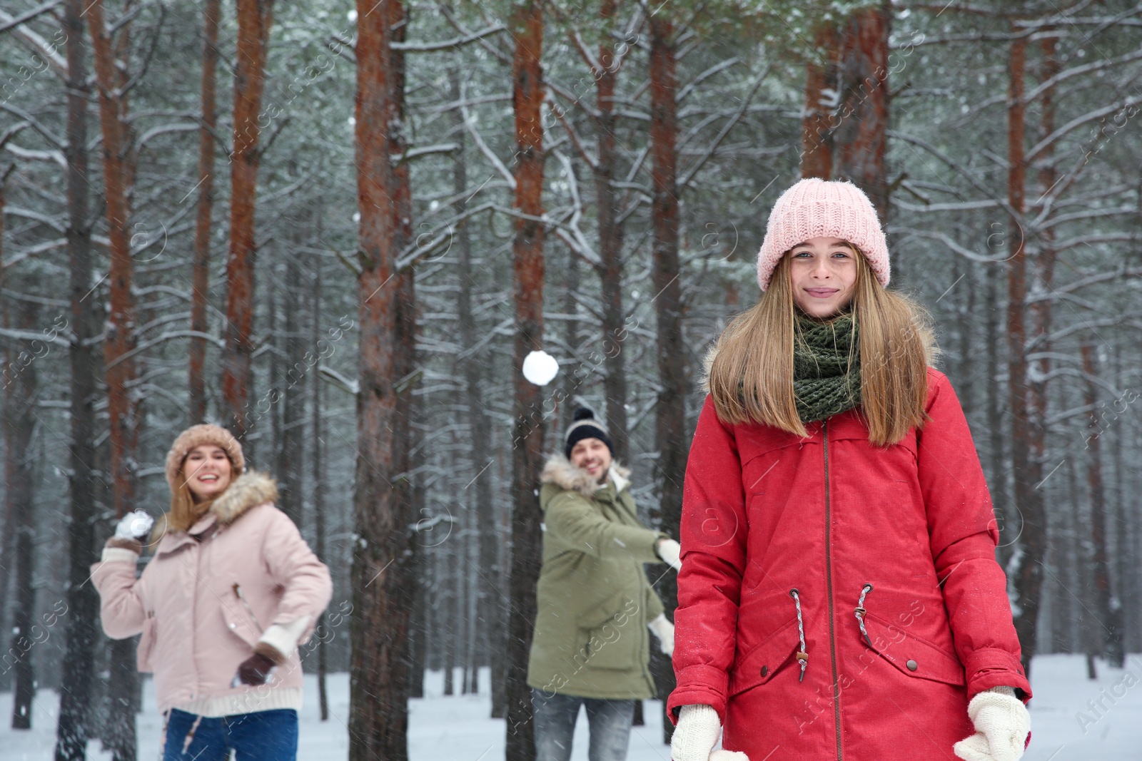 Photo of Teenage girl playing snowballs with family in winter forest