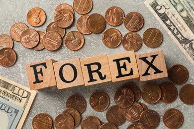 Photo of Word Forex made of wooden cubes with letters and coins on grey table, flat lay
