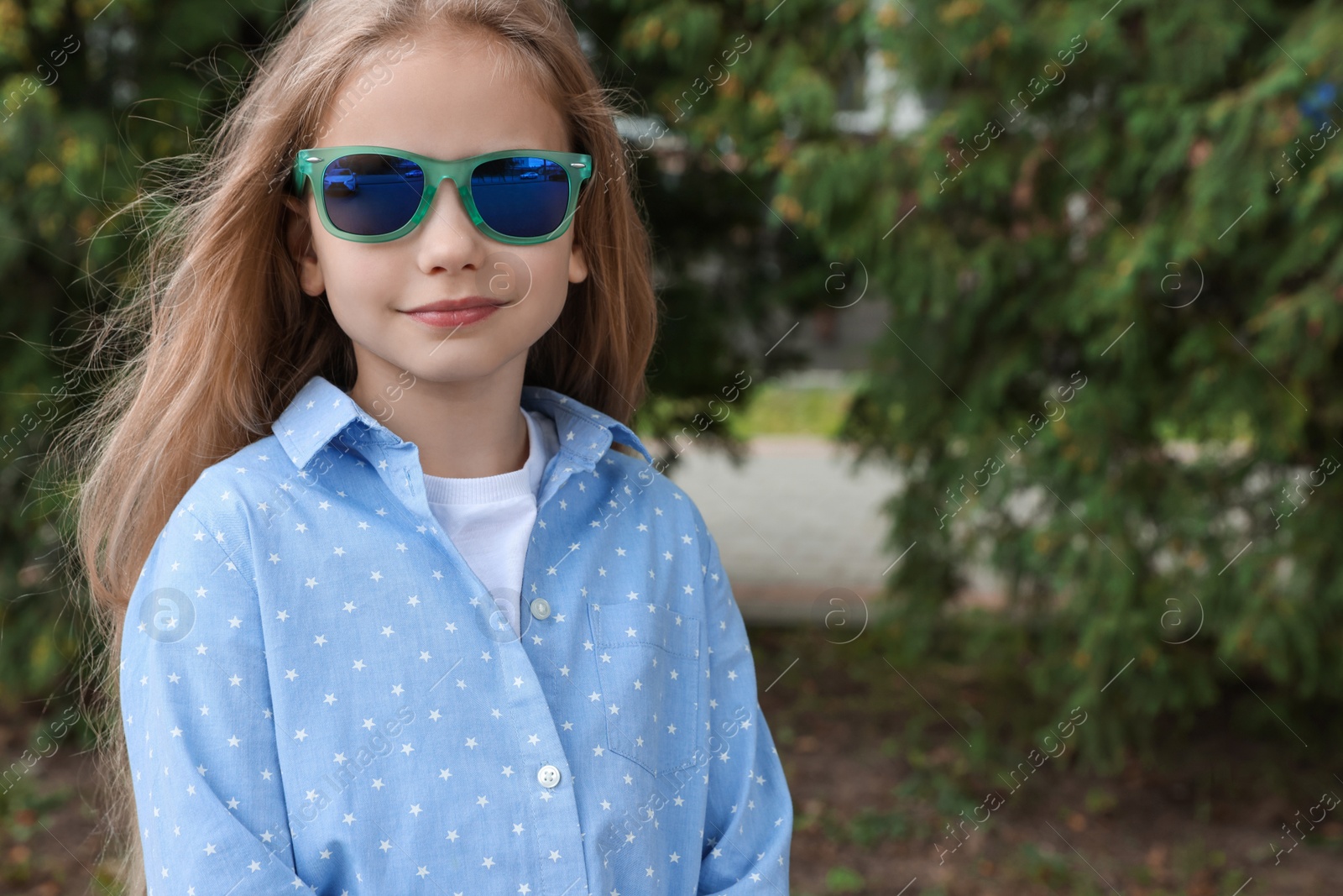 Photo of Girl in stylish sunglasses near spruce trees outdoors, space for text