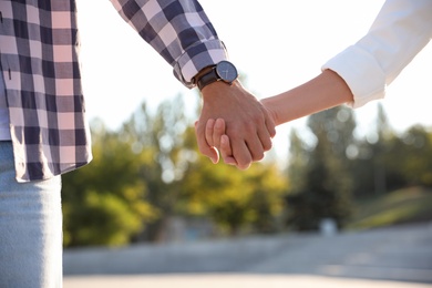 Photo of Couple holding hands together outdoors on summer day, closeup