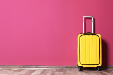 Photo of Bright yellow suitcase near color wall indoors