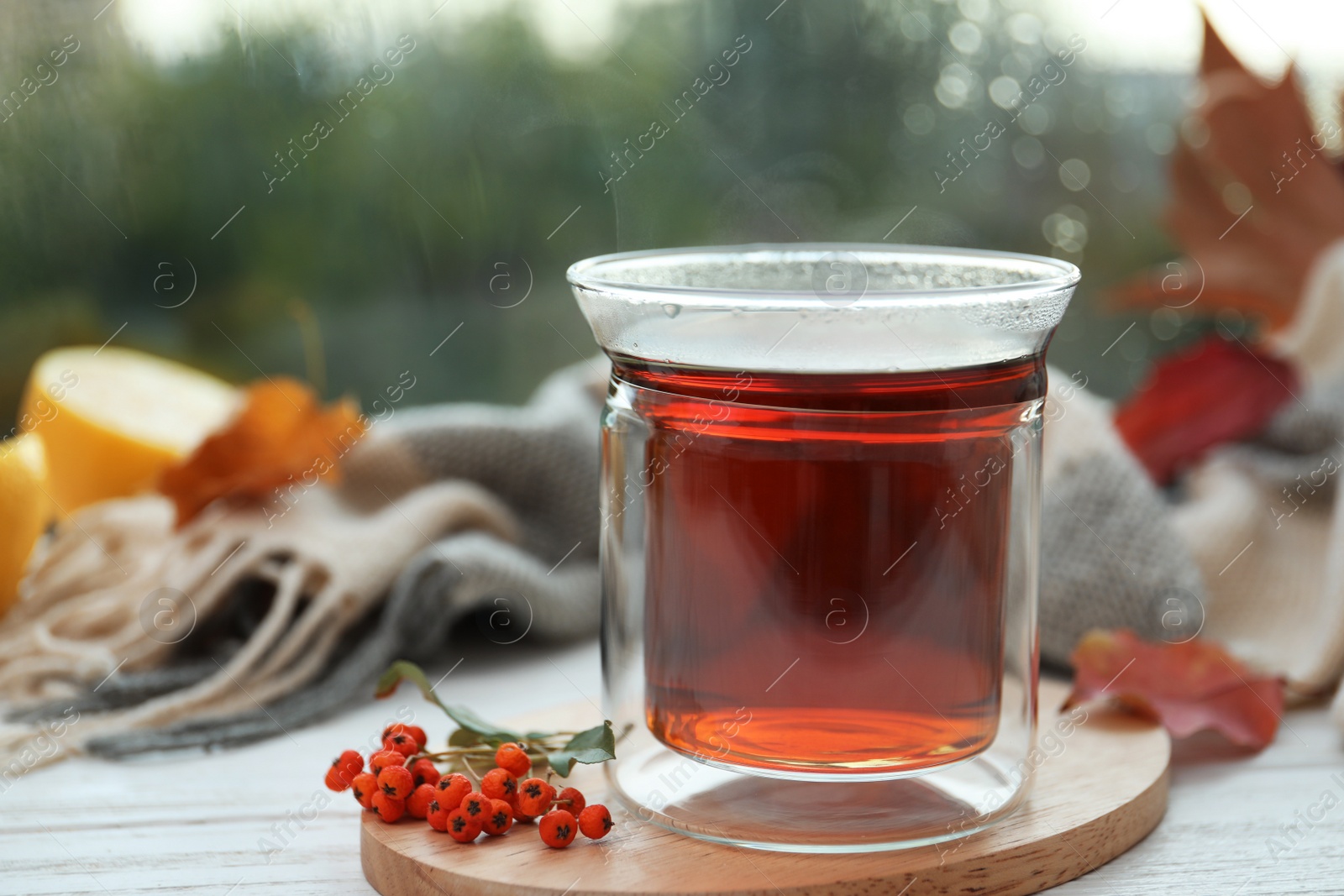 Photo of Cup of hot drink and scarf on window sill indoors. Cozy autumn atmosphere