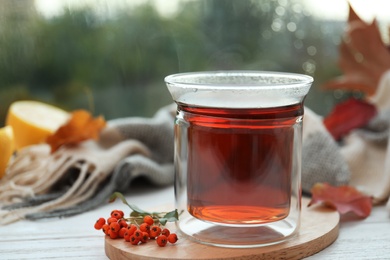 Cup of hot drink and scarf on window sill indoors. Cozy autumn atmosphere