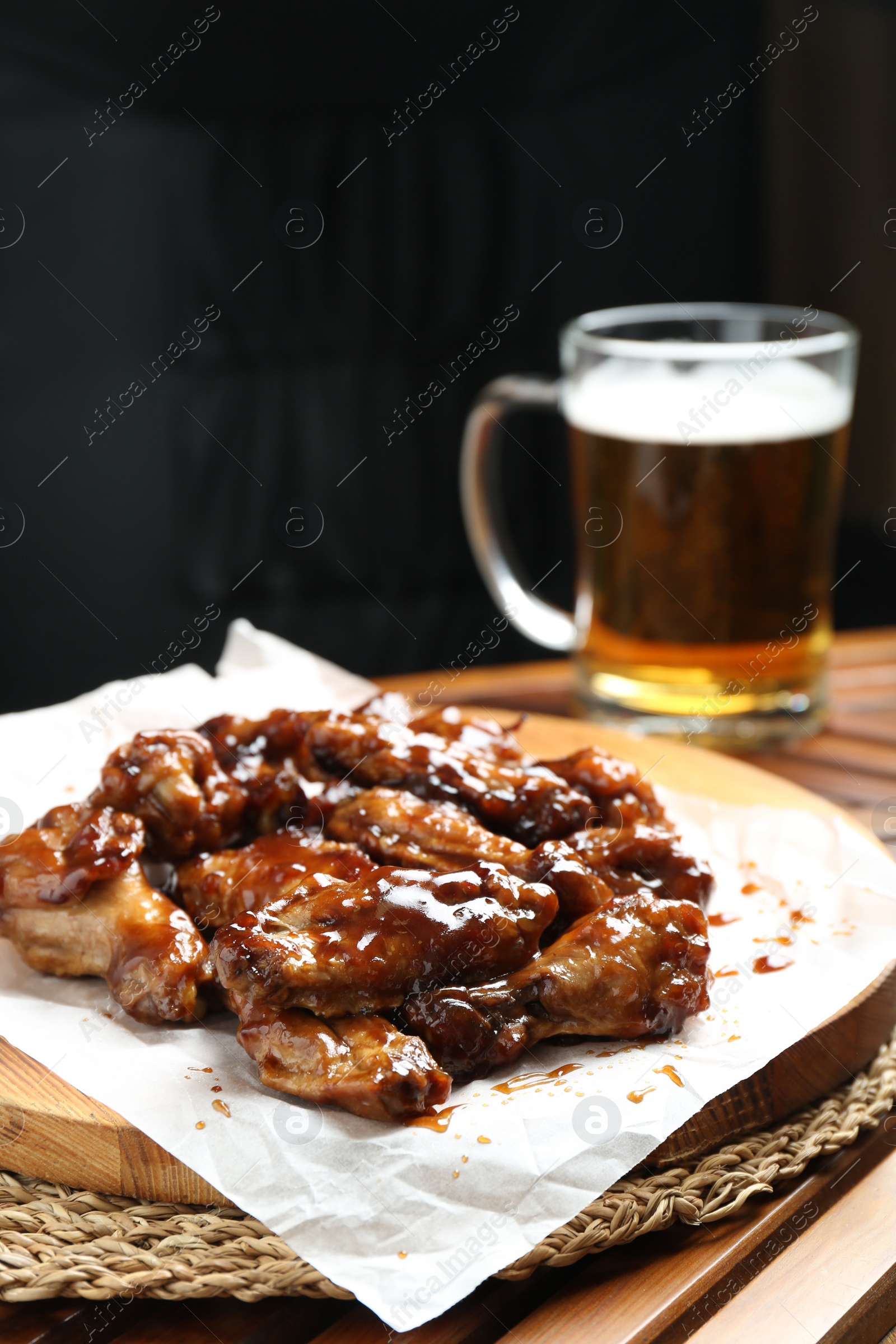 Photo of Tasty chicken wings and mug of beer on wooden table, space for text. Delicious snack