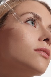 Photo of Beautiful woman applying cosmetic serum onto her face, closeup