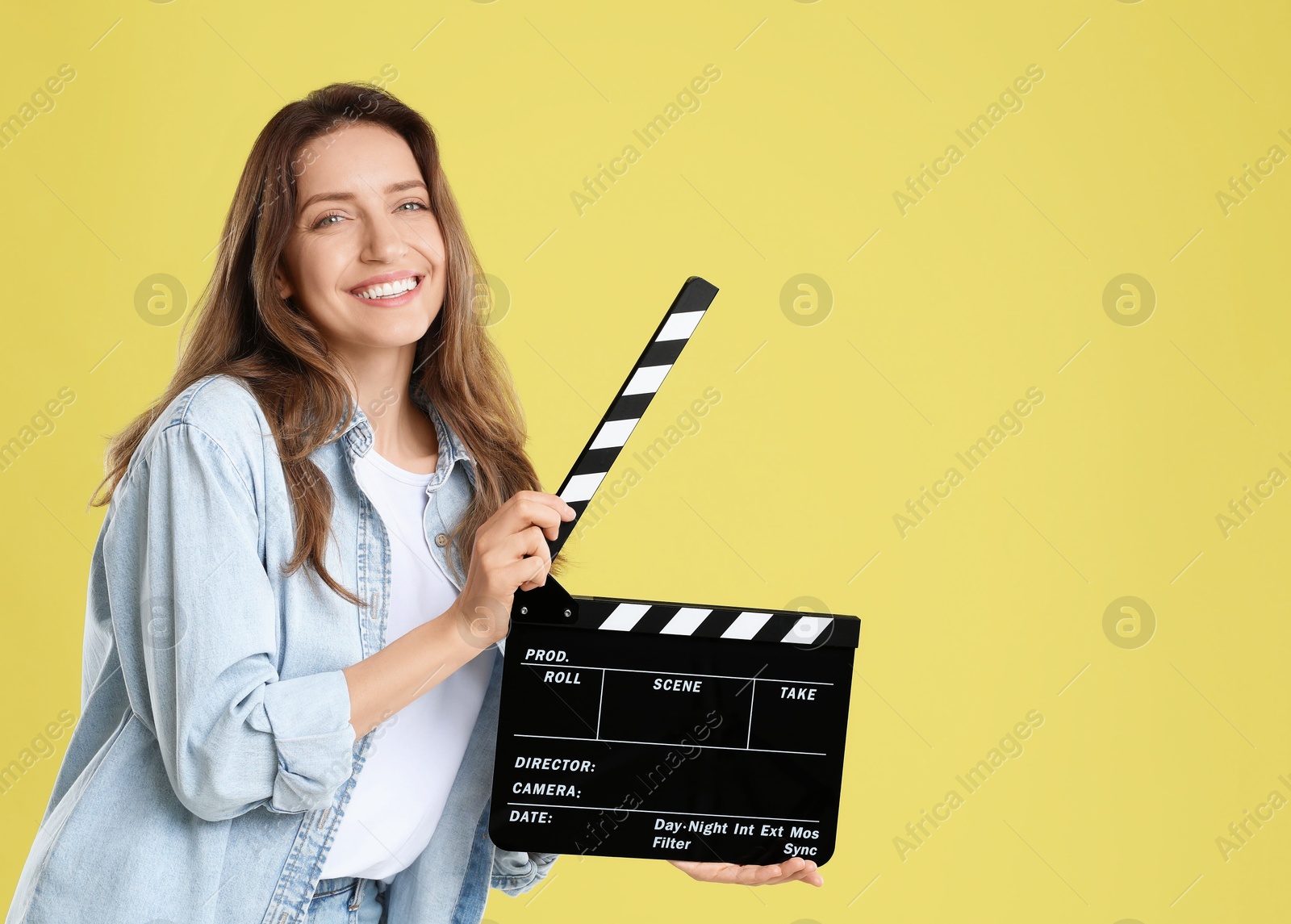 Photo of Making movie. Smiling woman with clapperboard on yellow background. Space for text