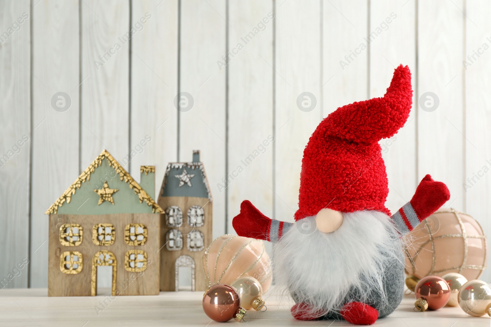 Photo of Cute Christmas gnome and festive decor on table against white wooden background, space for text