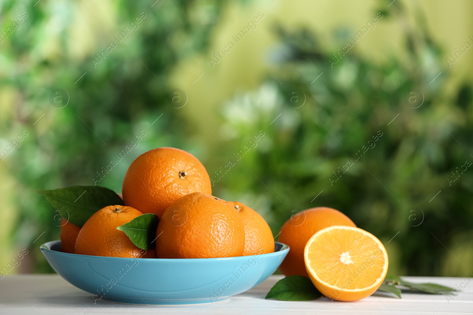 Photo of Fresh ripe oranges on white table against blurred background. Space for text