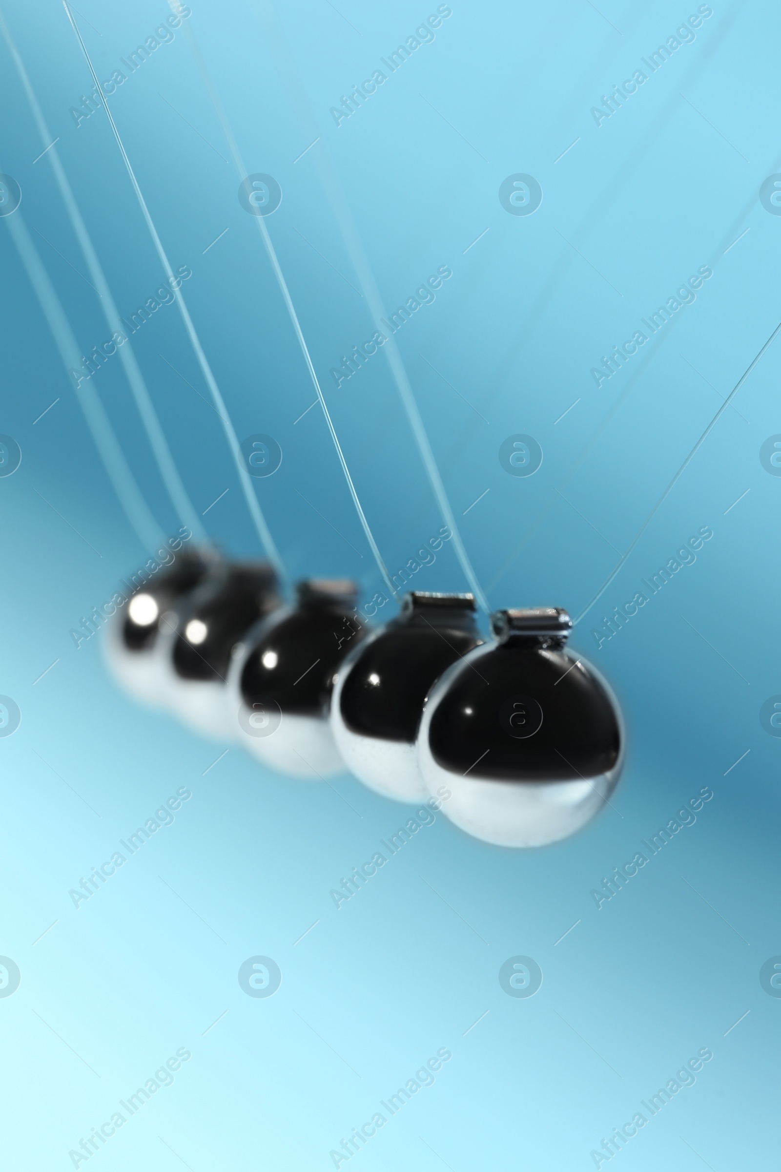 Photo of Newton's cradle on light blue background. Physics law of energy conservation