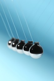 Newton's cradle on light blue background. Physics law of energy conservation