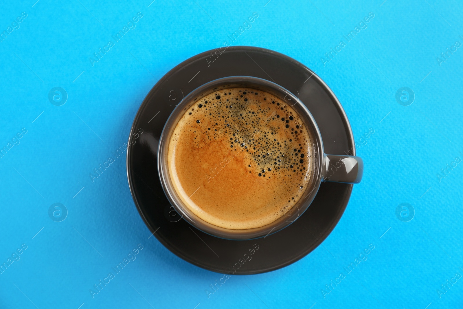 Photo of Cup of tasty coffee on light blue background, top view