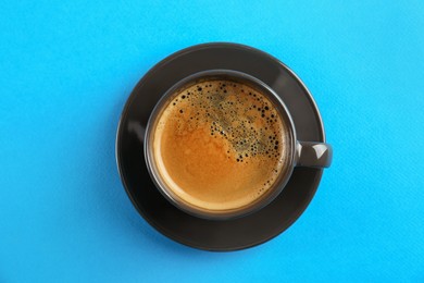 Photo of Cup of tasty coffee on light blue background, top view