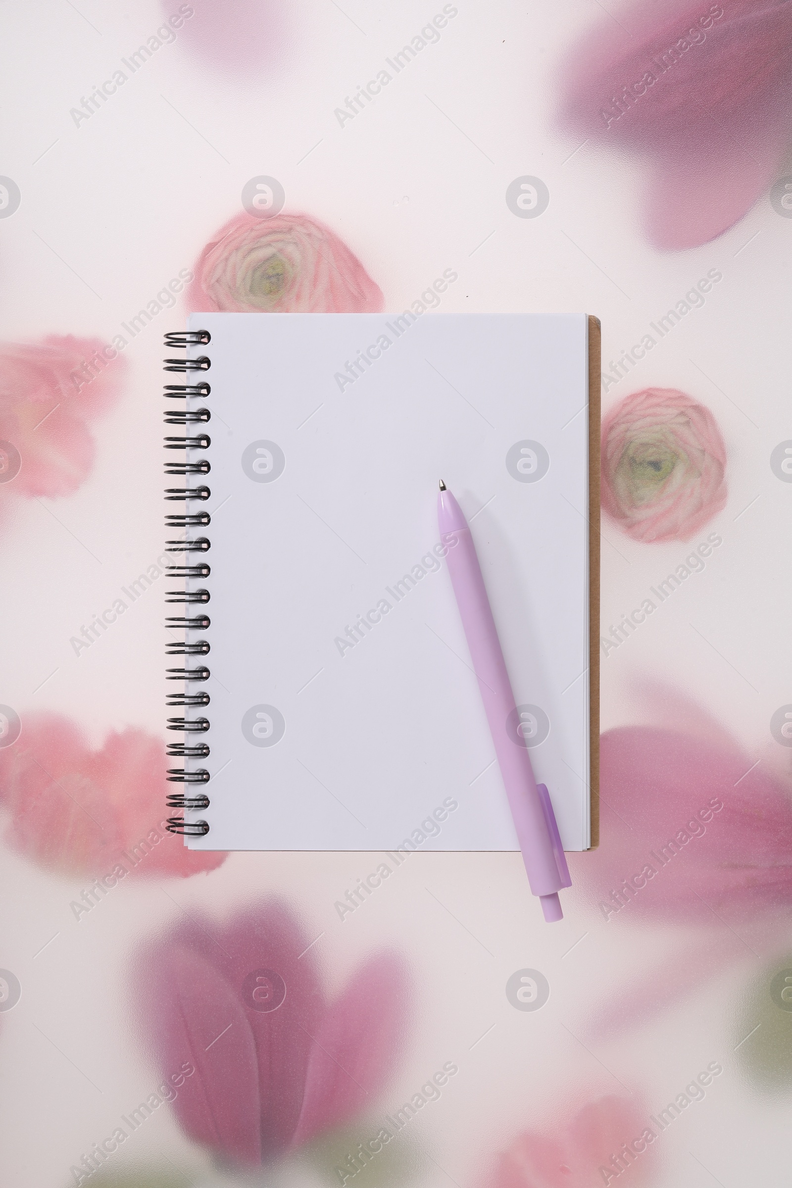 Photo of Guest list. Notebook and pen on spring floral background, top view