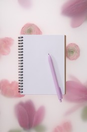 Photo of Guest list. Notebook and pen on spring floral background, top view