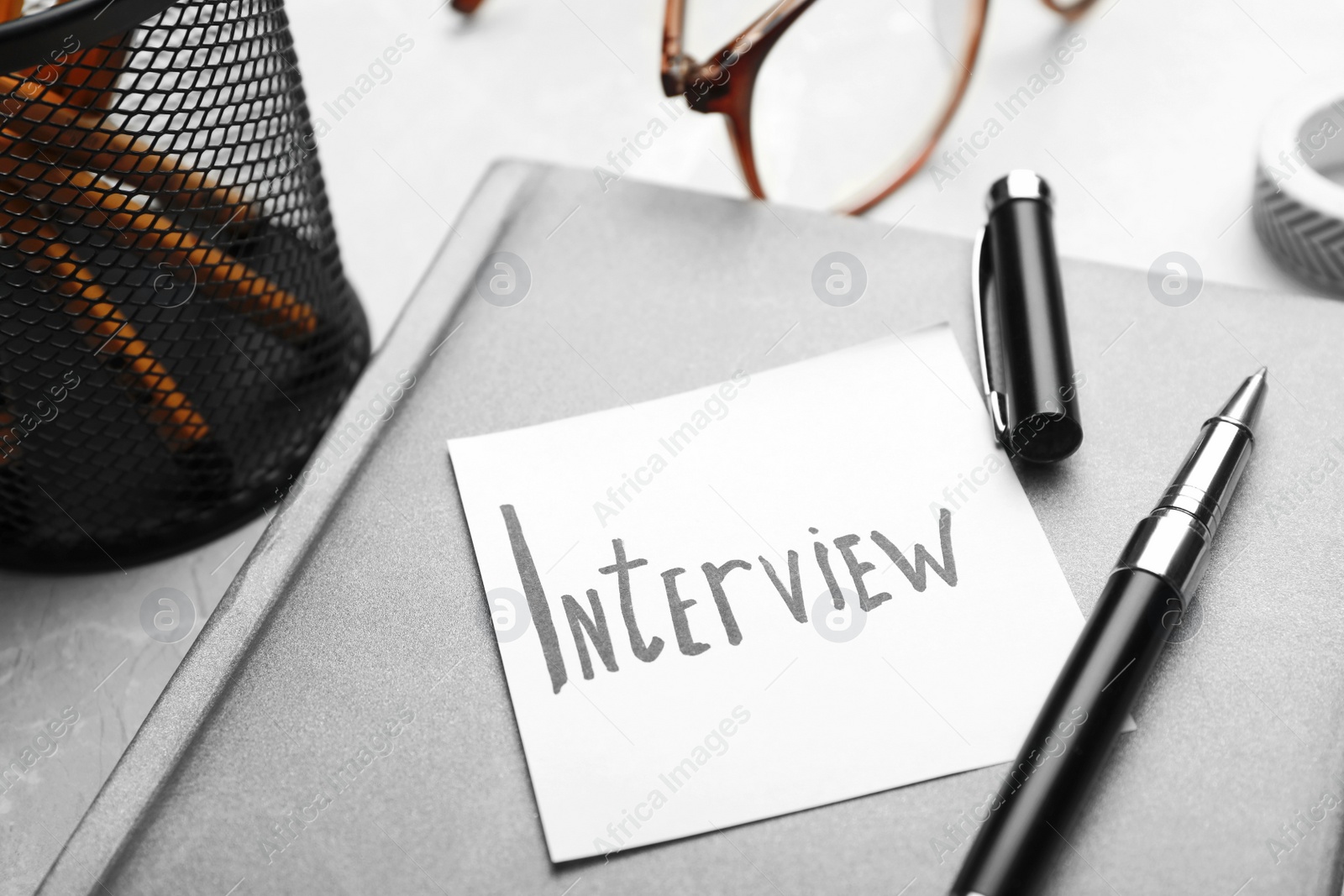 Photo of Reminder note about job interview and stationery on table, closeup